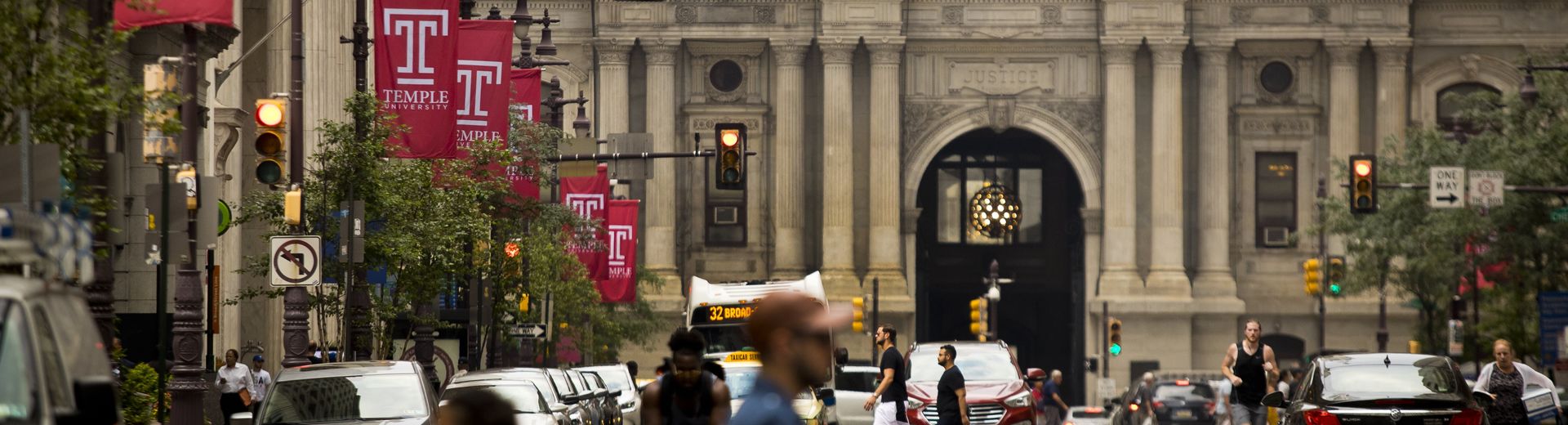 Temple University banners hang from street lamps, with Philadelphia's City Hall in the background.