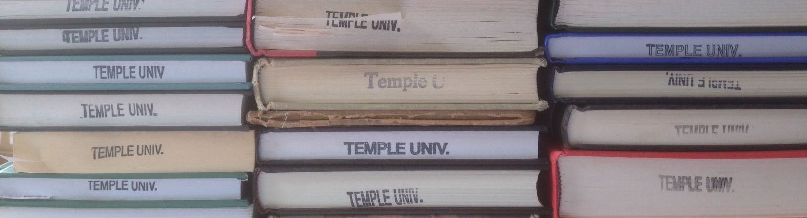 Three stacks of books, each stamped with the words "Temple University."