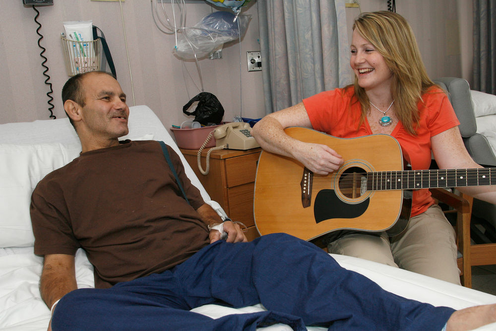  A music therapist plays guitar for a hospital patient.