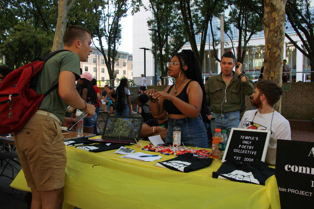 Creative writing students occupy a poetry table during an outdoors event on campus.