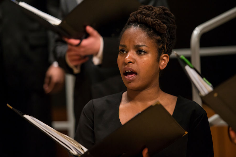 Choir singer holding musical score performing in a concert wearing black top