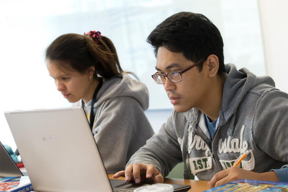 Two students work side by side on computers in a Temple classroom.