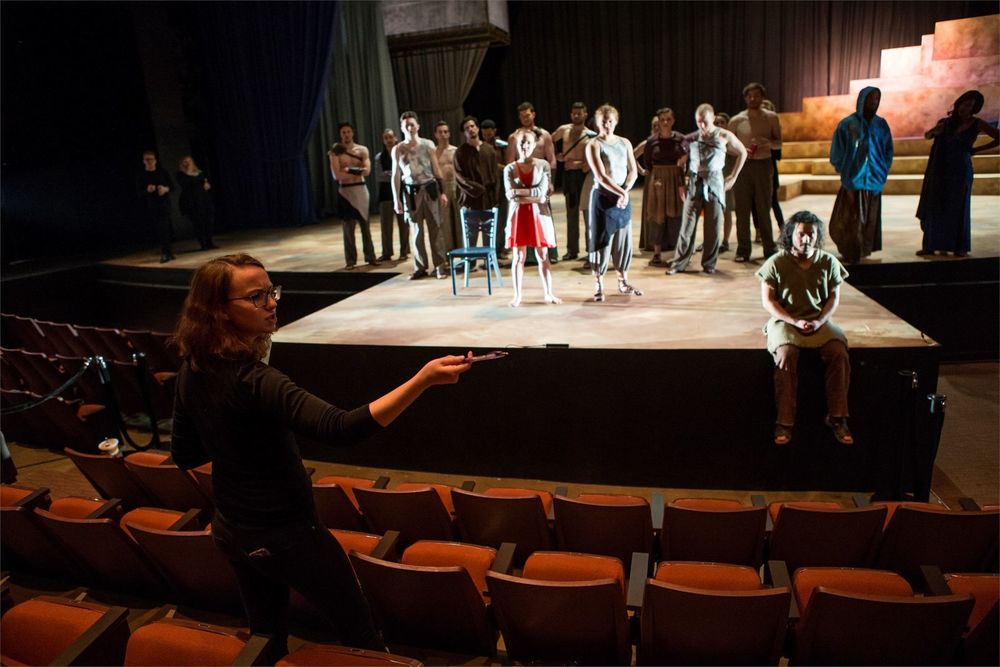 A female student is directing actors on stage.