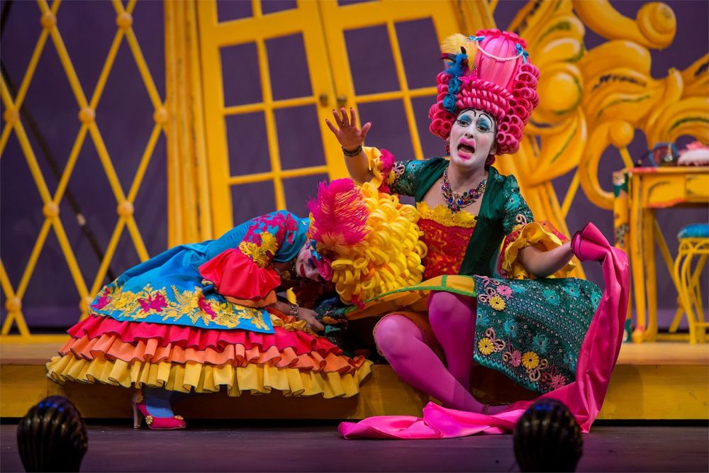 Opera singers wearing neon-colored costumes and wigs onstage.