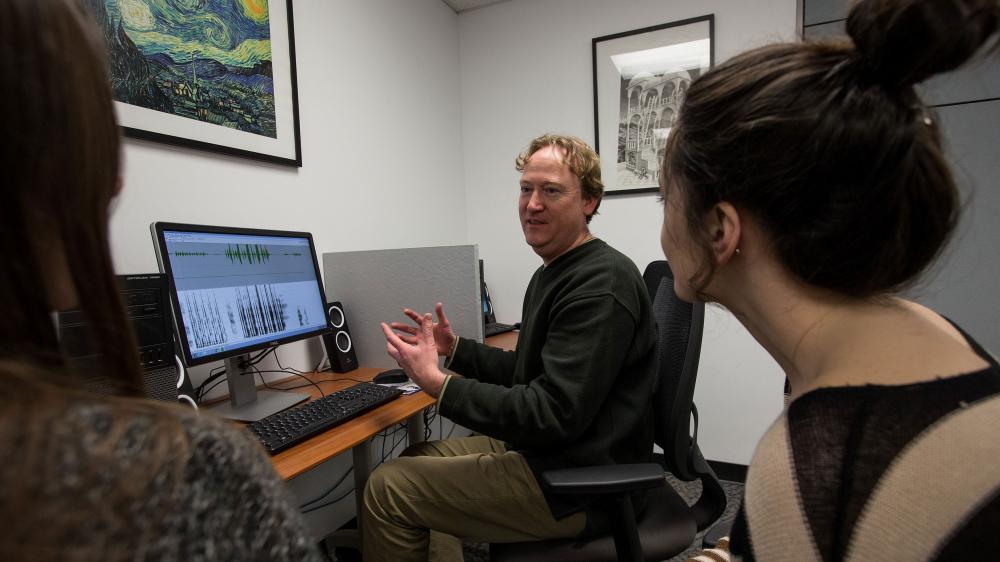 Linguistics professor with students in language lab