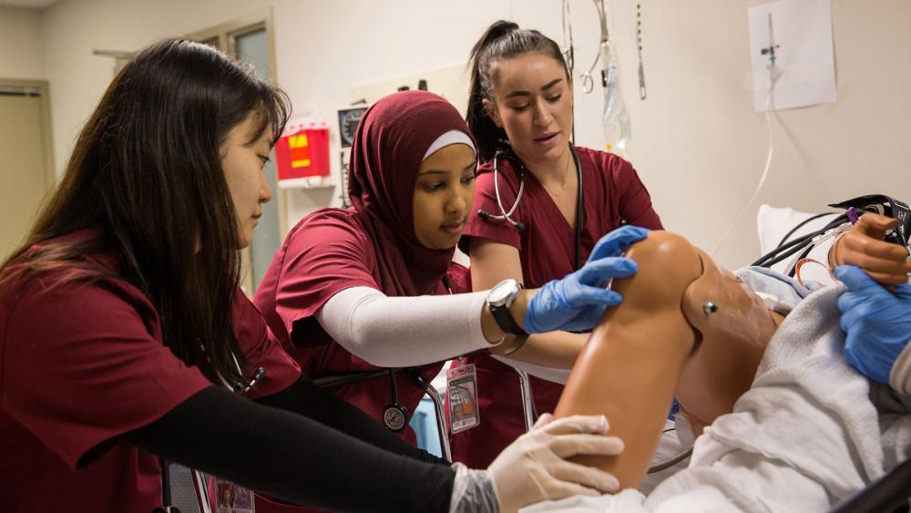 Temple nursing students conducting simulation on a mannequin in training lab.