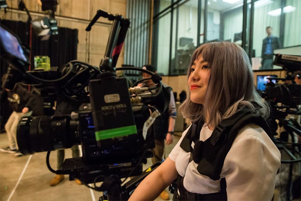 A film student sitting among film equipment in a film studio on campus.