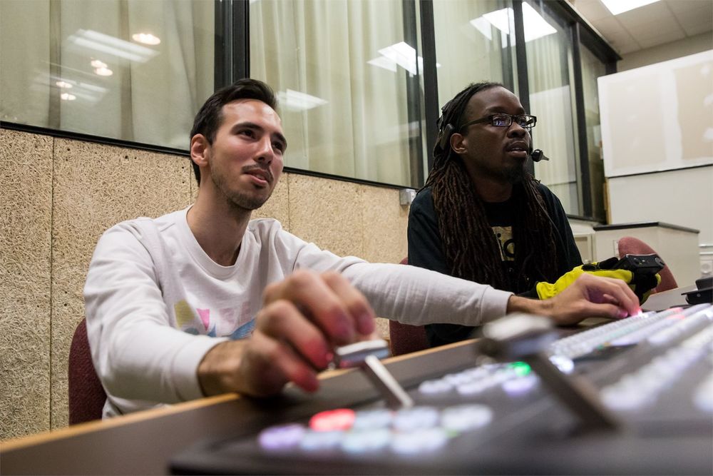 Two film students sitting behind a control panel.