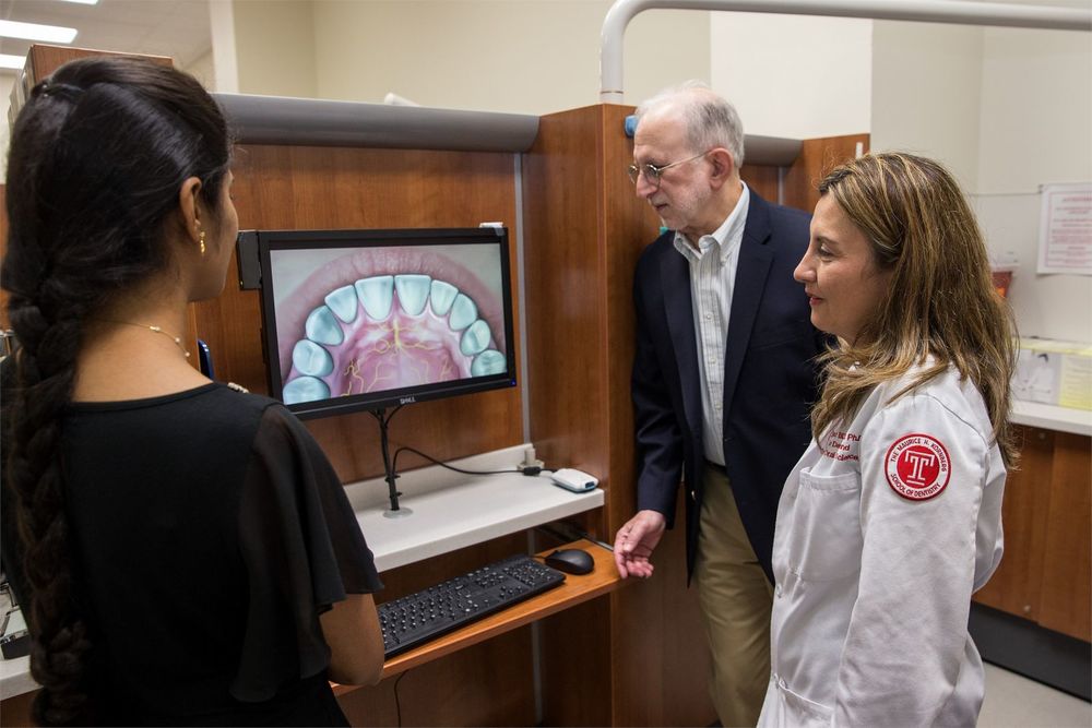 Temple dentist and student discussing the screened image of a mouth in a dental school clinic.