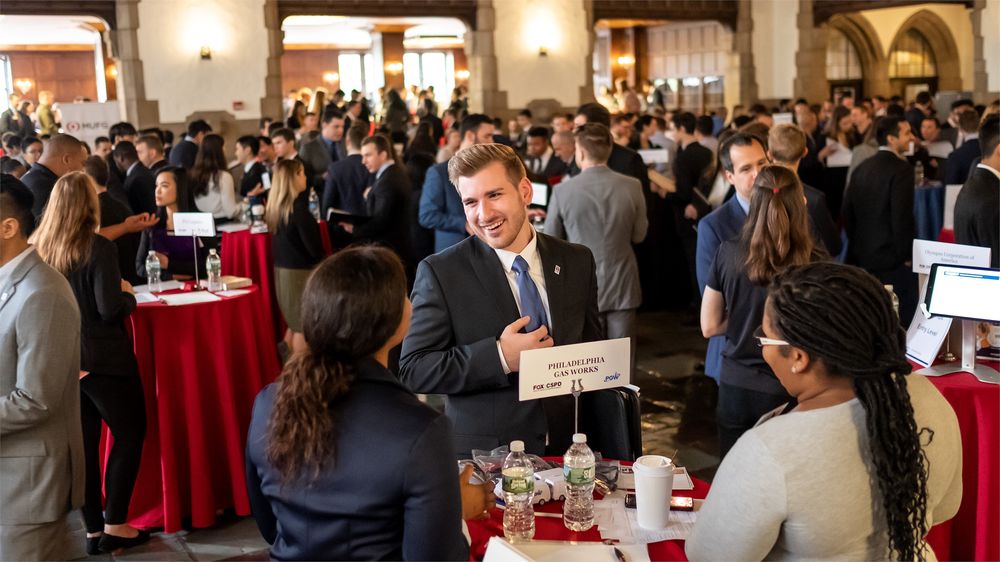 A student socializes at a networking event in a room full of people.