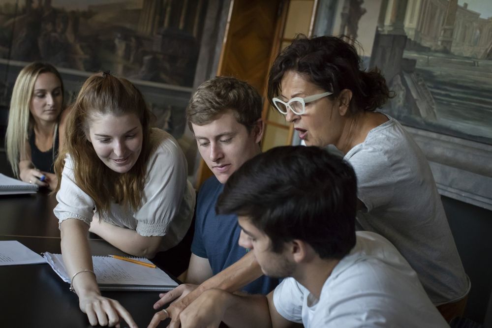 A teacher and four students discuss their work.