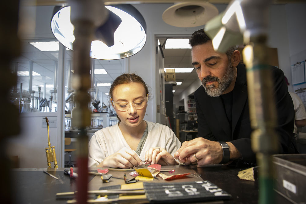 A professor assists a student in the Metals studio.