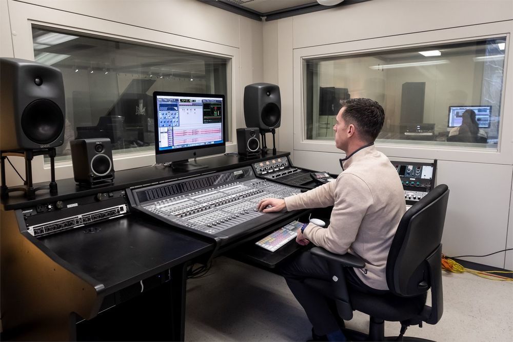 Student working at a computer and large panel in a music tech lab.