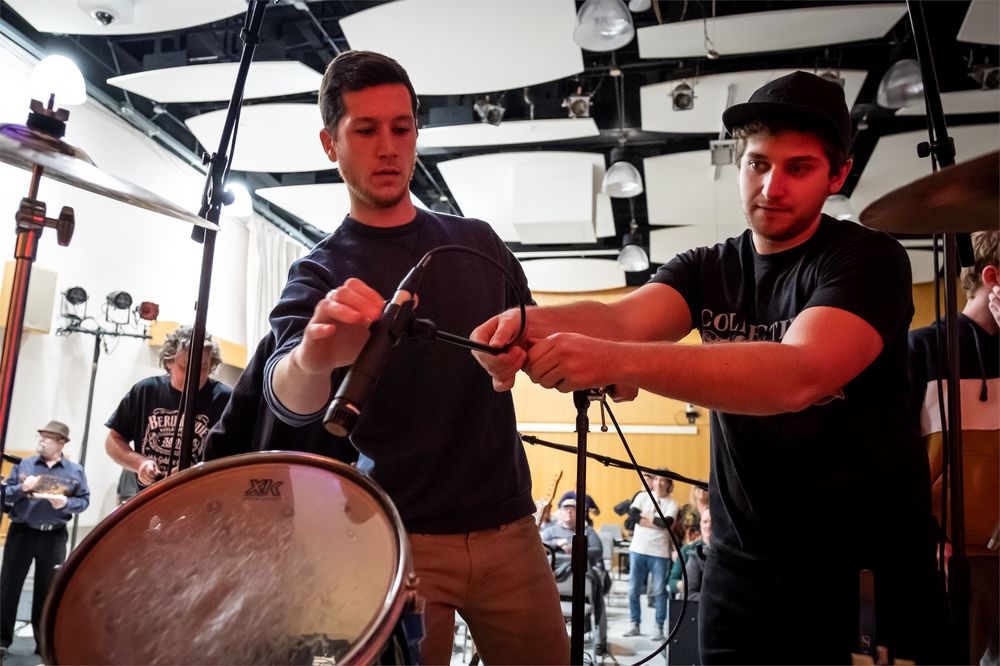 Two students set up microphones for a music recording session.