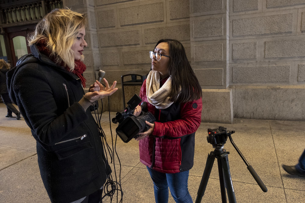 A student reporter talks with a source on the street.