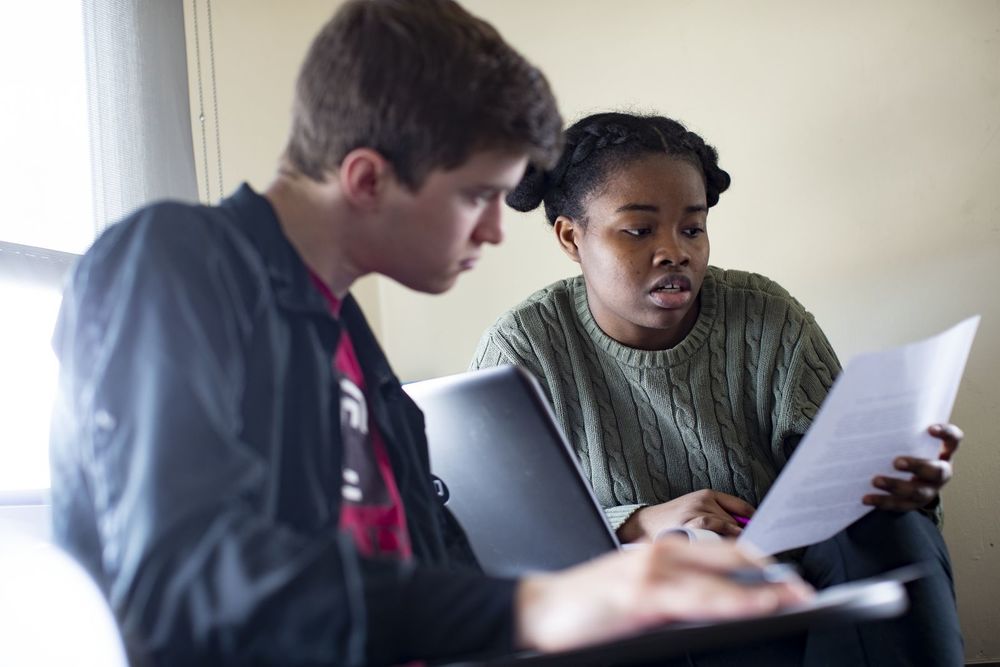 Two students read a paper together.