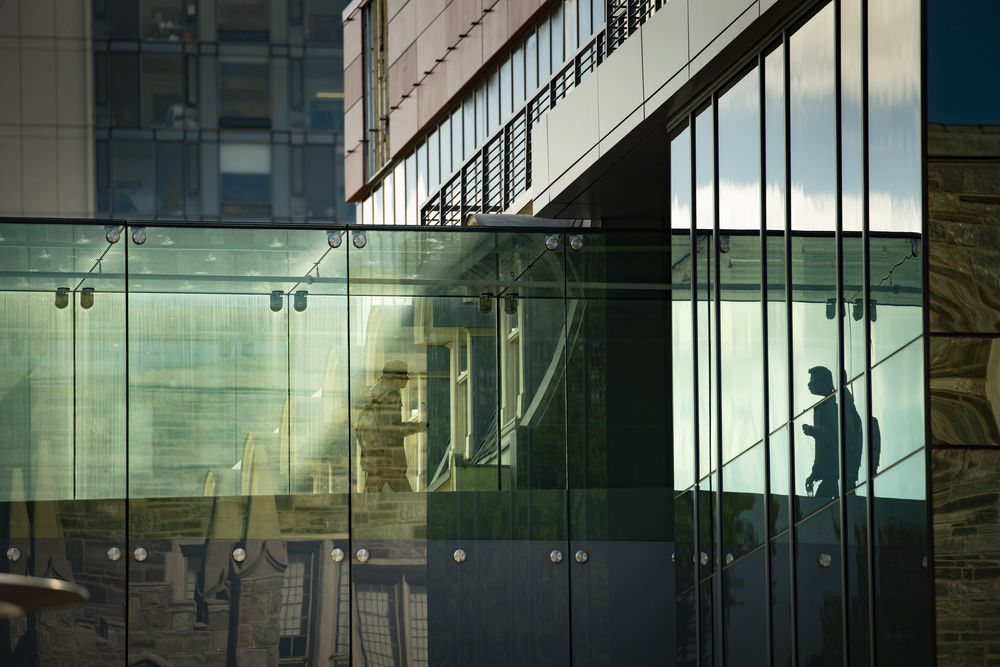 A student walks across the glass bridge between buildings on Temple's main campus.