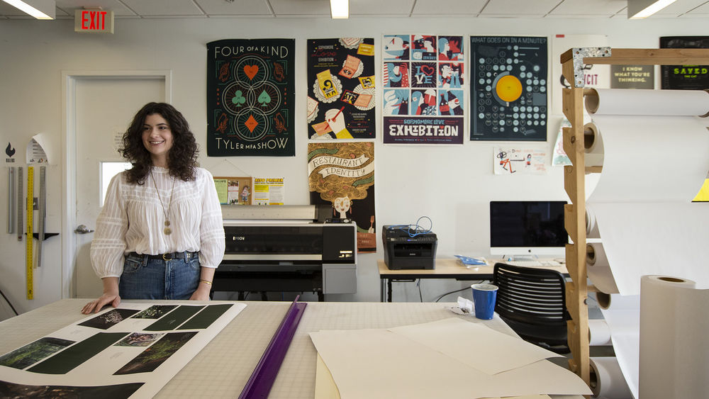 GAID student standing next to their work. 