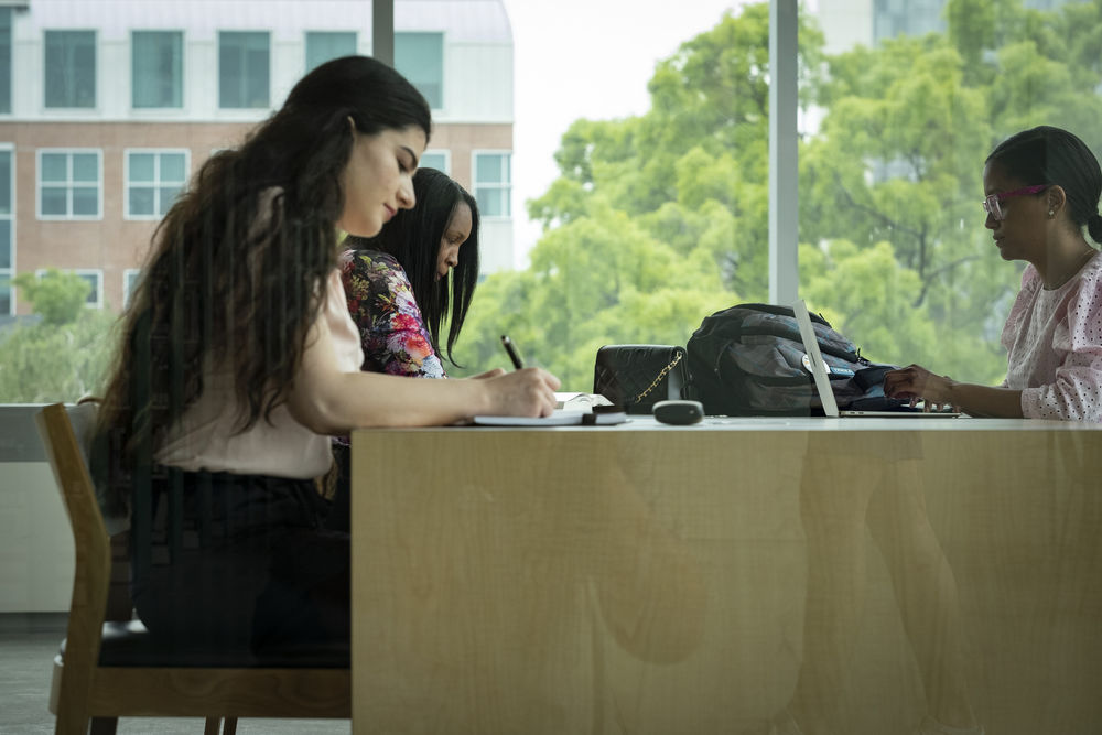 Three students studying at a table in the library