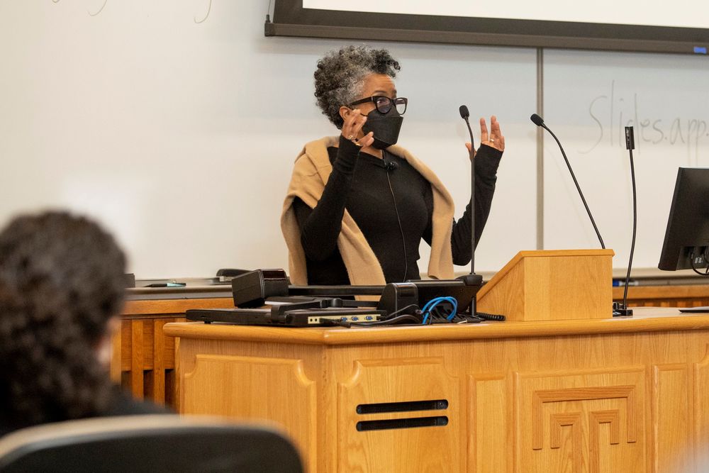 A person wearing a mask stands at a podium with their arms raised.