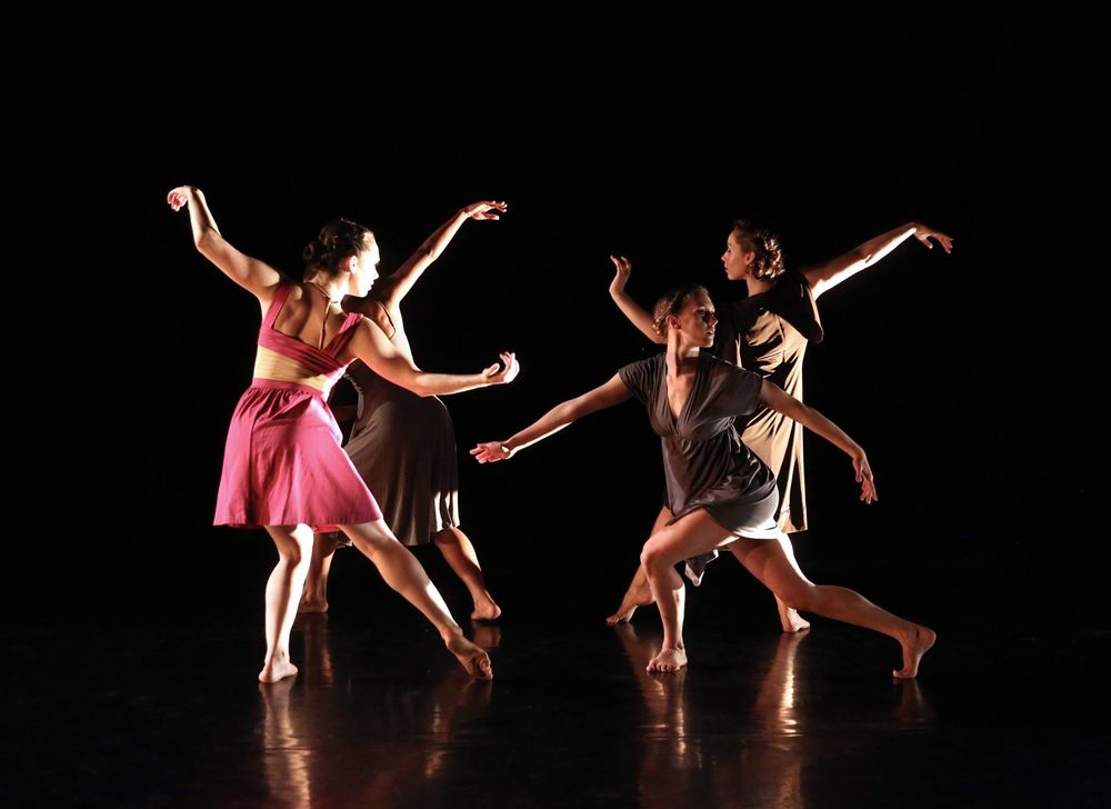 Four dancers perform on stage in a circle.