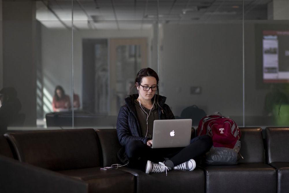 A Fox student works intently in a lounge on the main floor of Alter Hall.