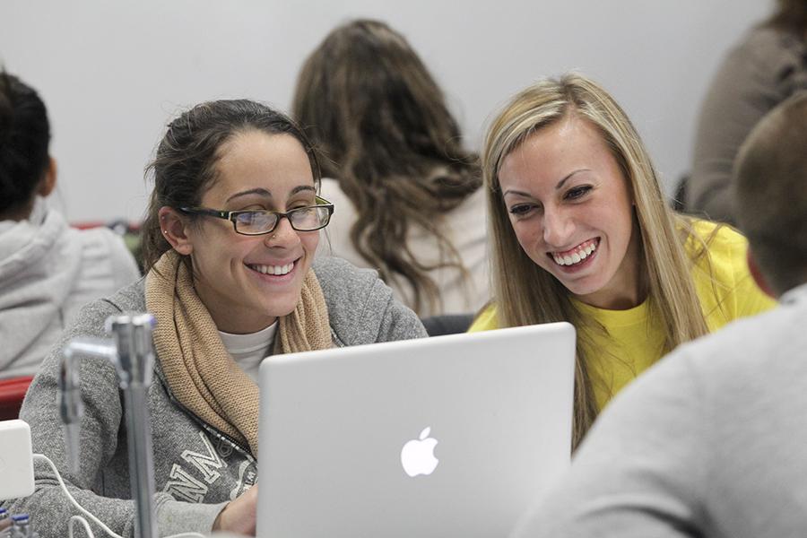 Students collaborating in front of a laptop in class