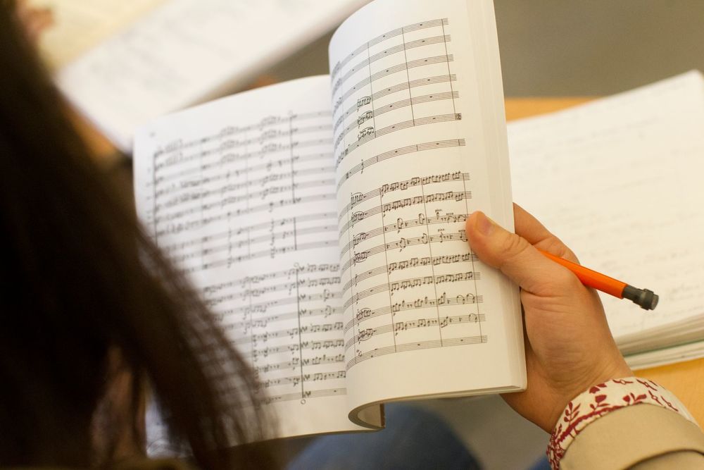 A student reads a book of sheet music.