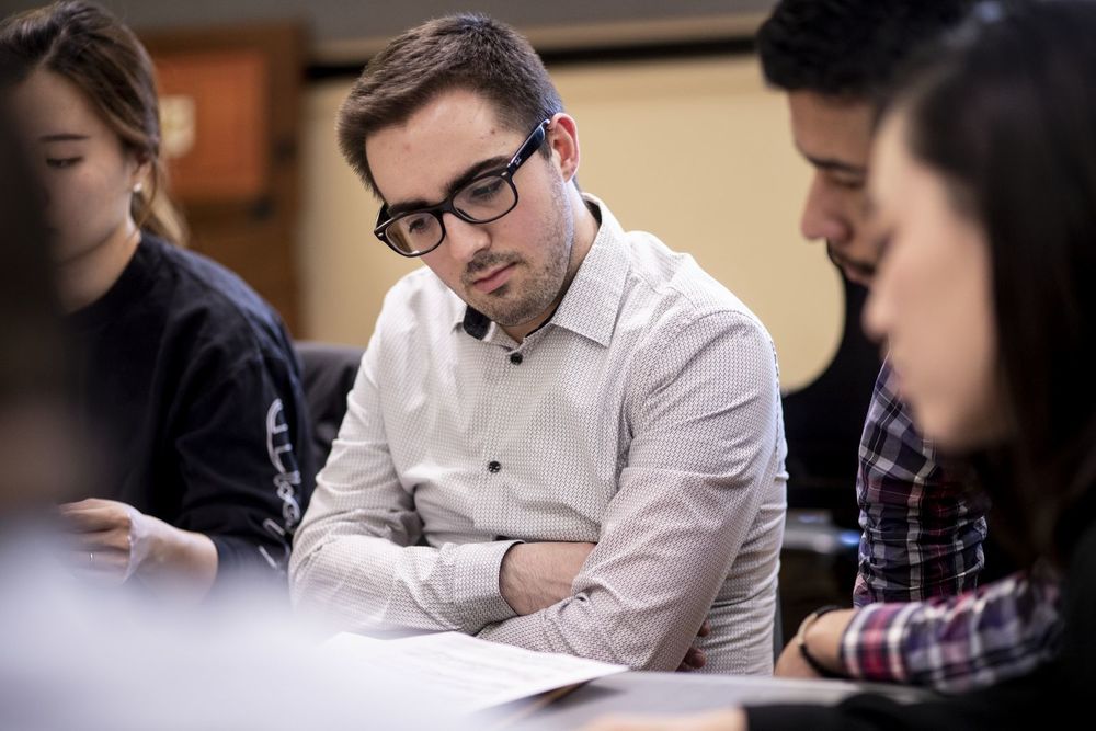 Boyer College of Music and Dance students sit in a classroom together and examine papers in front of them.