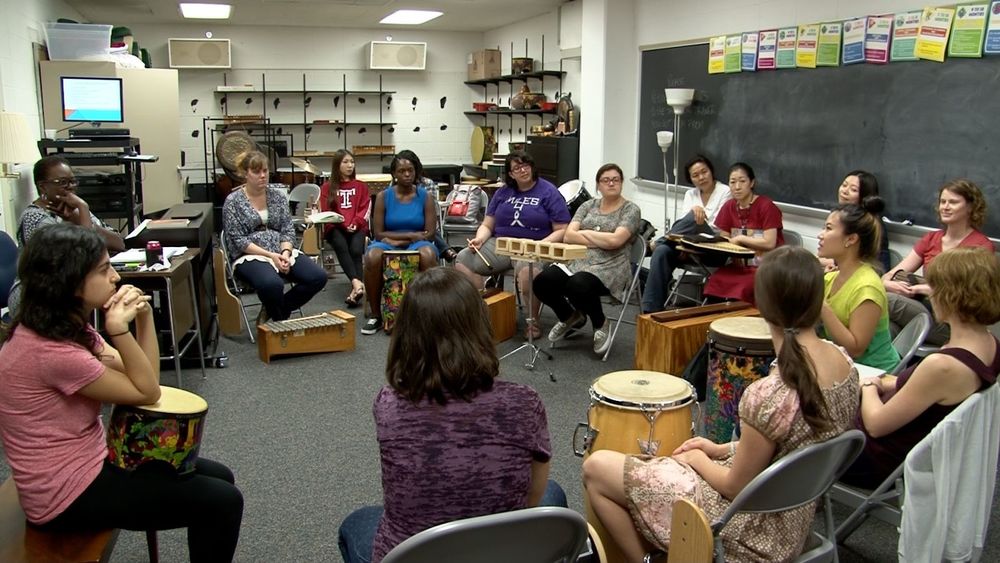 Music Therapy Jazz students sit in a circle in a classroom with different kinds of percussion instruments in front of them.