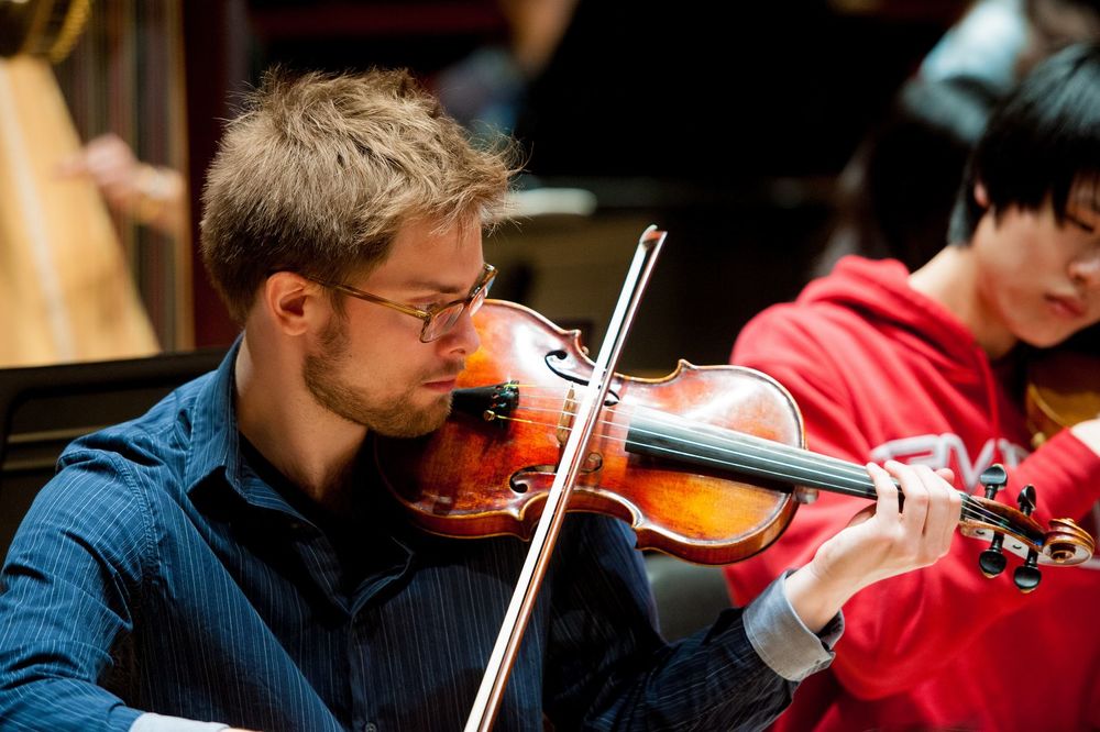 Student plays the violin during rehearsal.