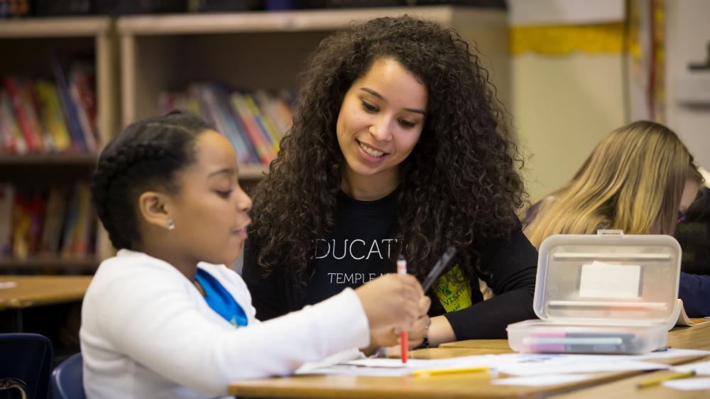 education student working with a young learner in elementary school classroom