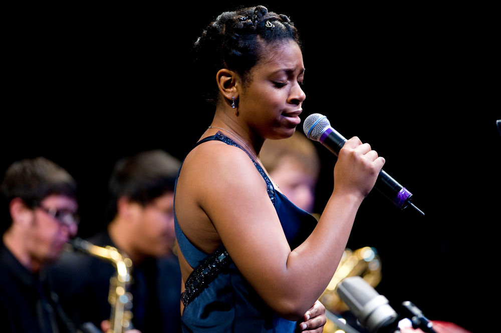 Jazz singer performing on stage with a band.