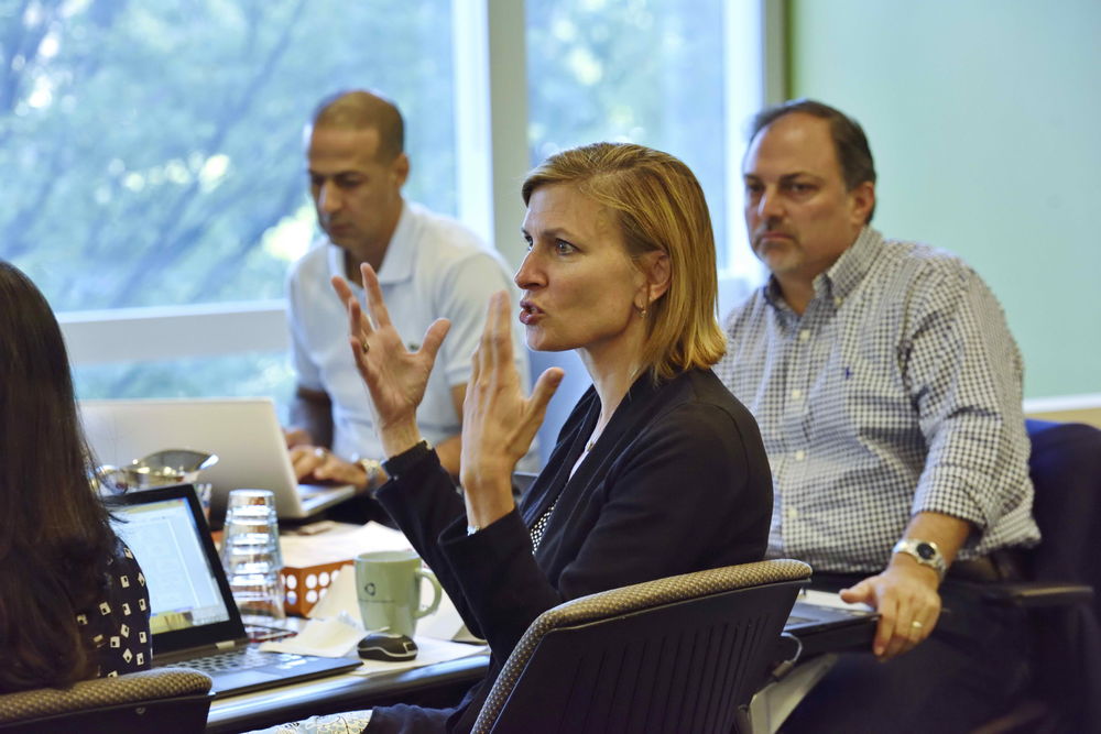 A woman speaking passionately in a classroom while students listen closely.